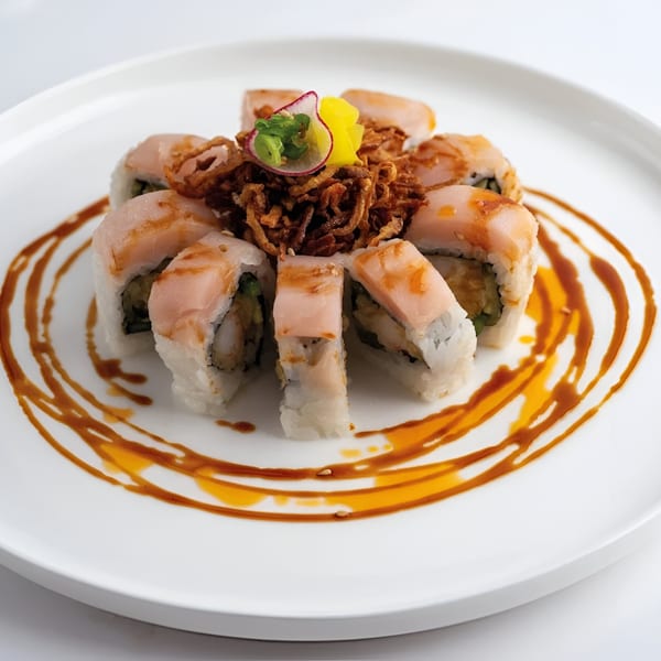 Mama M Sushi roll with white fish, crispy onions, and a drizzle of sauce on a white plate.