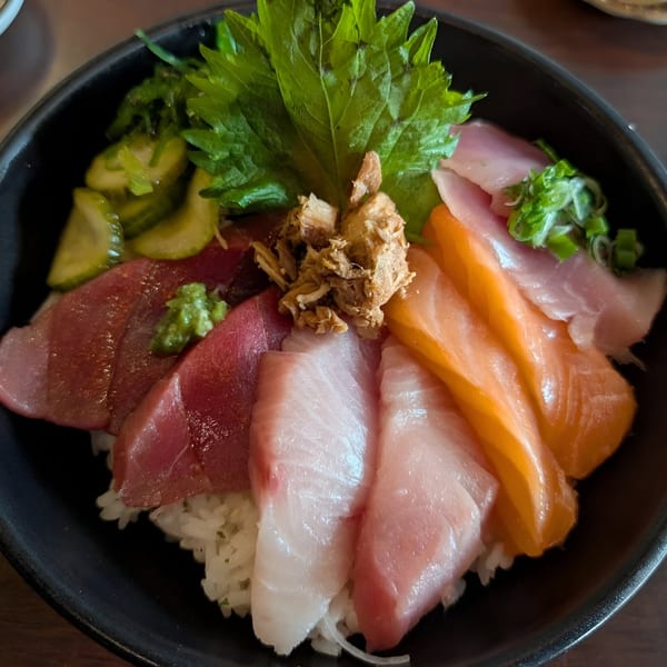 A colorful Mama M Sushi chirashi bowl with various sashimi, rice, and garnishes.