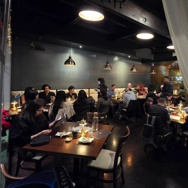 Diners enjoying a meal in the dimly lit, modern interior of Mama M Sushi restaurant.